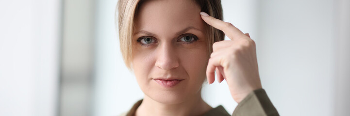 Portrait of a thinking woman with a finger on the forehead