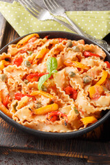 Bell pepper and Creamy Tomato Sauce is a sweet and simple match for chunky ribbon-shaped reginette mafaldine pasta closeup on the plate on the table. Vertical