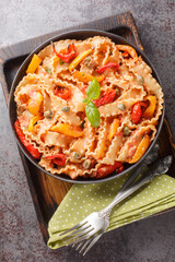 Mafalda Pasta in Creamy Tomato Sauce with capers and baked papper closeup on the plate on the table. Vertical top view from above