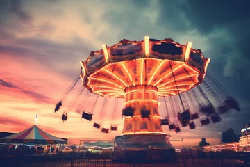 Foto op Plexiglas a fairground ride shot at night toned with a retro vintage filter action effect against a pink and blue cloudy sky © sam