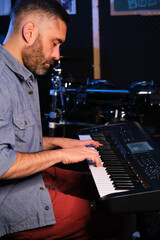 Musician man playing keyboard synthesizer piano in a recording studio. Music production.