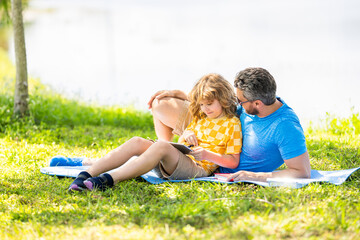 son with father bonding in summer. family education of father and son kid. Father shapes son education with tablet. Father and son relax in park. childhood school education. learning in nature