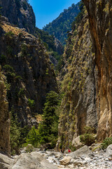 Hikers in a narrow gorge with huge, towering cliffs either side (Samaria Gorge, Greece)
