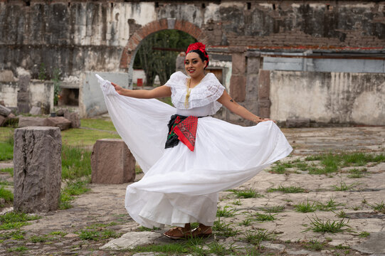 Mexican folk dancer woman from the state of nayarit, Mexican pink nayarrita folk costume with blue, fan and dancing with skirt and turns on black background