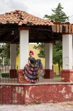 Mexican folk dancer woman from the state of nayarit, Mexican pink nayarrita folk costume with blue, fan and dancing with skirt and turns on black background
