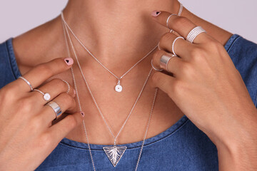 Close up of hands with silver rings and neck with silver necklaces