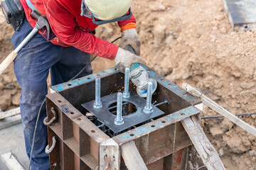 Worker using grinding machine to cut support metal plate foundation.