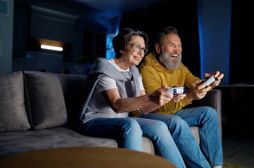 Senior couple playing video games together at home