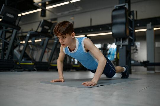 Teenager healthy boy making gymnastics pushup while training at gym