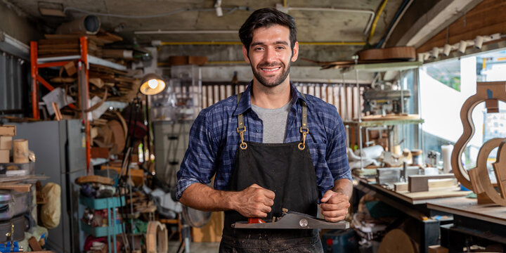 Lute and acoustic instrument manufacturing shop. Man wearing plaid shirt making guitar. Planning guitar back. Luthier's workshop.