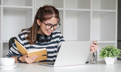 Asian female student study online in class, study online, wearing headphones, watching video call, zooming, happy asian female learning language online with computer laptop.