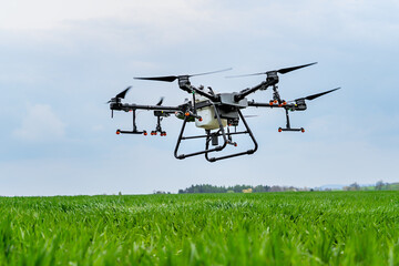 Drone flying over a green grass field with cloudy sky in the background