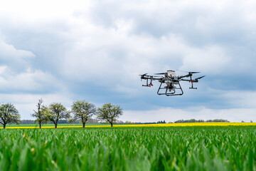 Drone flying over a green field with yellow flowers and cloudy sky