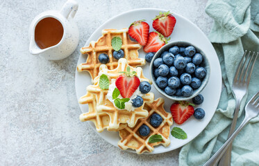 Freshly baked waffles with strawberries and blueberries - obrazy, fototapety, plakaty