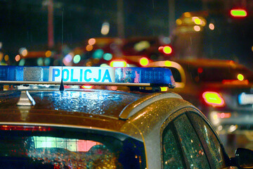 W nocy radiowóz policji polskiej w czasie deszczu na patrolu.