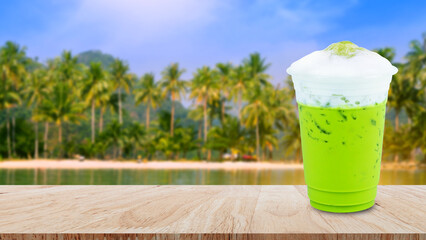 Iced matcha green tea latte frappuccino with milk foam in takeaway cup on wooden table, Summer drinks with iced