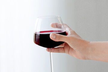 female hand with red wine glass on a white background