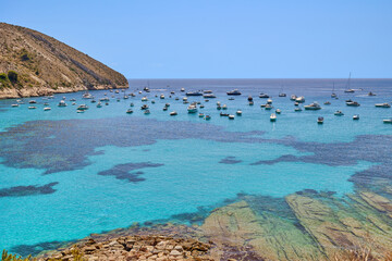 Fototapeta premium View of yachts and boats moored on the small bay with clear turquoise water, also known as Cala El Portet, the Costa Blanca region of Spain.