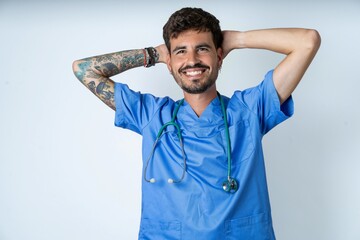 young caucasian doctor man wearing blue medical uniform stretching arms, relaxed position.