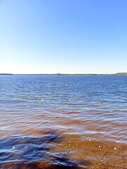 Panorama of the water surface of the wide Dnieper covered with a small ripple under a clear blue sky.