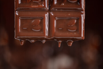 Melted chocolate drips down on a brown background.