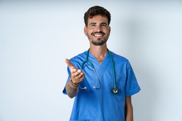young caucasian doctor man wearing blue medical uniform smiling cheerful offering palm hand giving...