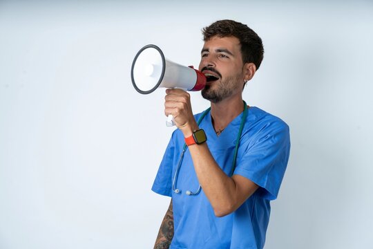 young caucasian doctor man wearing blue medical uniform Through Megaphone with Available Copy Space