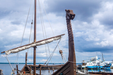 figurehead on the bow of a full-scale replica of a viking ship, moored in port - obrazy, fototapety, plakaty