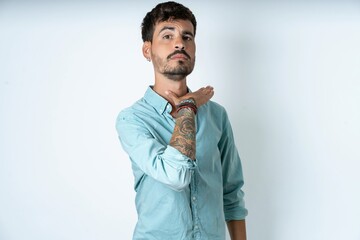 young caucasian man wearing green shirt cutting throat with hand as knife, threaten aggression with...
