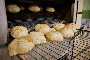Baking traditional egyptian flatbread aish baladi. Freshly baked pita bread from oven. Traditional...