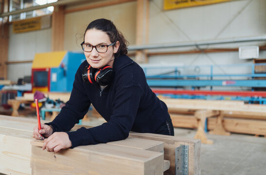 Female Carpenter Drawing on Wooden Beam in Production Hall