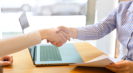 Women shake hands at business meetings, signing a contract. A business handshake, the end of the meeting, a laptop on the table, a businessman's office