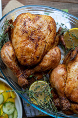 Roast chicken with lemon and herbs on a wooden background. Top view