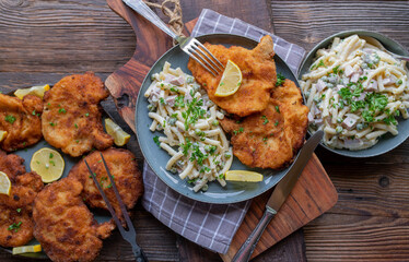 Traditional german meal with breaded cutlets and pasta salad on wooden table background. Top view