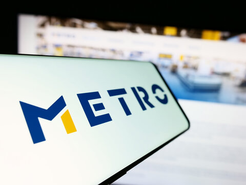 Stuttgart, Germany - 08-22-2023: Cellphone with logo of German wholesale company Metro AG on screen in front of business website. Focus on center-left of phone display.