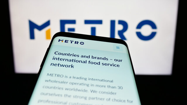 Stuttgart, Germany - 08-22-2023: Mobile phone with website of German wholesale company Metro AG on screen in front of business logo. Focus on top-left of phone display.