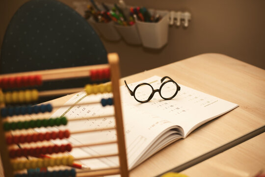 Children's desk with glasses, math workbook, wooden abacus