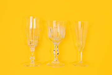 Three vintage crystal glasses on a yellow background. Minimal concept.