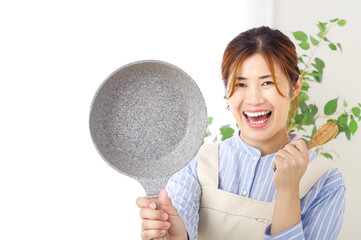 調理器具を持つ元気な女性のイメージ