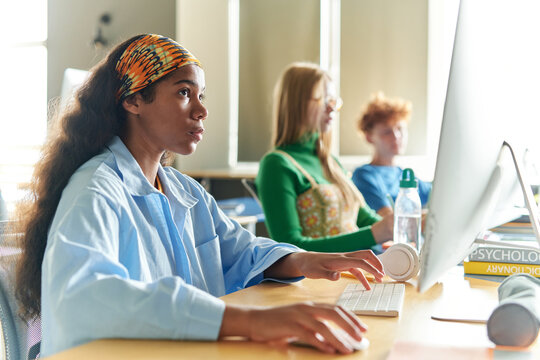 Group of students sitting at desk and learning on computers at class