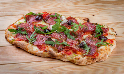 Pizza Diavolo with chorizo, rucola, jalapeno, chili, kalamata, pesto. Roman pizza rectangular on wood background