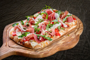 Sorrentina pizza with prosciutto, arugula, capers, pelati sauce, pesto. Roman pizza rectangular on...