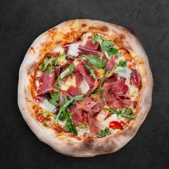 Foto auf Acrylglas Sorrentina pizza with prosciutto, arugula, capers, pelati sauce, pesto. Neapolitan round pizza on dark background © GrumJum