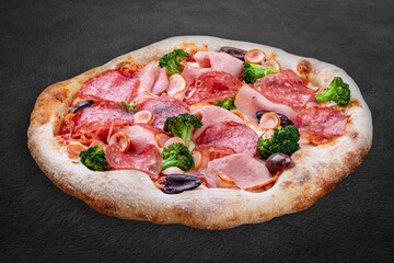 Pizza with salami, ham, vienna sausages, kalamata, olives, broccoli, pelati, pesto. Neapolitan round pizza on dark background
