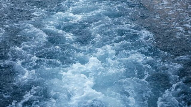 Close-up of the seething water in the sea behind the ship. Sea. A splash of sea waves behind a large boat at sea. Slow movement.