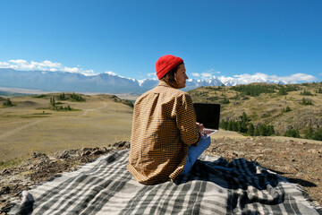 Back view woman freelancer traveler working online using laptop and enjoying the beautiful nature...