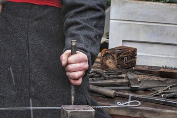 Close-up of authentic blacksmith working with hammer and iron at anvil of workshop. Traditional...
