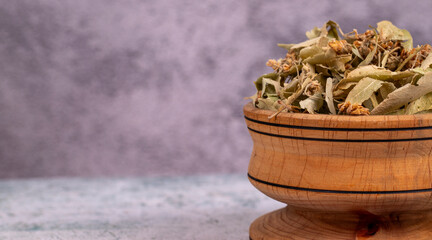 Fototapeta na wymiar Dried linden flowers. Fresh flowers and leaves of linden in wood bowl on a grey background. Herbal medicine. Copy space. Empty space for text