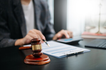 Fototapeta premium justice and law concept.law theme wooden desk, books, balance. Male judge in a courtroom the gavel,working with digital tablet computer on table.