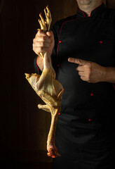 Raw fresh chicken in chef hands before cooking. Selected a rooster for frying in a restaurant kitchen. Dark background for menu or recipe hotel © Віталій Б.